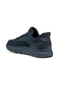 Sneaker blu navy realizzato in una combinazione di materiali in suede e pelle, con suola texturizzata e un design ondulato prominente sulla suola esterna.