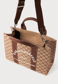 Bolso tote de Karl Lagerfeld Paris de tela marrón con patrón, asas dobles, correas desmontables, bolsillo frontal y compartimento interior con cremallera visible.
