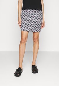 Gonna con motivo nero e rosa dal design aderente, lunghezza sopra il ginocchio, abbinata a scarpe nere aperte davanti con suola spessa.