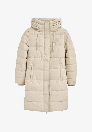 Veste matelassée beige avec capuche, présentant des surpiqûres horizontales, deux poches latérales et des cordons ajustables sur la capuche.