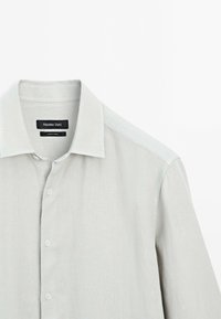 Light gray linen shirt with a classic collar, front buttons, and a tag reading "Massimo Dutti." Smooth texture and casual design.