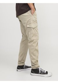 Beige cargobyxor med flera fickor, raka ben och elastiska muddar. I kombination med svarta högklackade sneakers med vita snören.