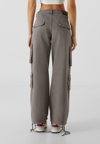 Pantalons cargo gris, avec poches latérales, coupe ample et ourlets à cordon de serrage. Fabriqués en tissu texturé avec des poches arrière renforcées.