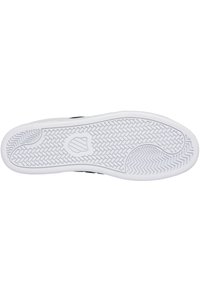 Svart sneaker sula med en vit gummiyttersula. Har ett strukturerat greppmönster med cirkulära och zigzag-spår för bra fäste.