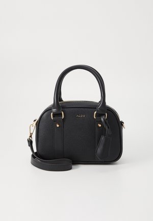 Sac à main en cuir noir texturé avec deux poignées, une bandoulière détachable, des ferrures dorées et une petite étiquette suspendue près d'une poignée.