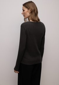 Maglione grigio scuro a coste con scollo rotondo e maniche lunghe, caratterizzato da una texture morbida e una silhouette aderente.