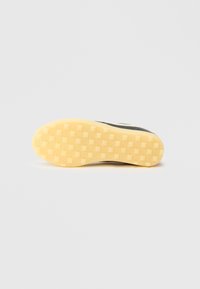 Jalatsipõhi ümarate servadega, kollase kummipõhjaga, millel on ruuduline muster ja tekstuuriga pind haarduvuse tagamiseks.