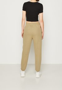 Svart kortärmad t-shirt kombinerad med khaki sweatpants. Byxorna har en elastisk midja och fickor, med en slät tygtextur och avsmalnande ben.