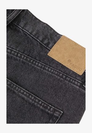 Poche arrière et ceinture d'un jean en denim noir avec une étiquette rectangulaire en cuir brun brodée sur la ceinture.