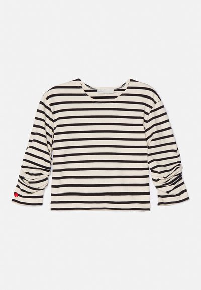 Striped long-sleeve top in cream and black, featuring a round neckline and ruched detailing on sleeves. Small red flower accent on cuff.