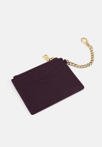 Purple leather wallet with a textured wave design, gold chain attachment, and zip closure. Slim, rectangular shape with card slots.