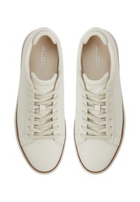 Zapatillas de cuero blanco texturizado con cordones planos y un perfil bajo. Cuenta con una suela de goma marrón y un logo grabado en la plantilla.