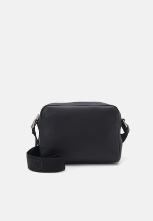 Borsa a tracolla nera in pelle con forma rettangolare, chiusura con zip e una tracolla in tessuto con logo. Superficie texturizzata con un branding sottile.