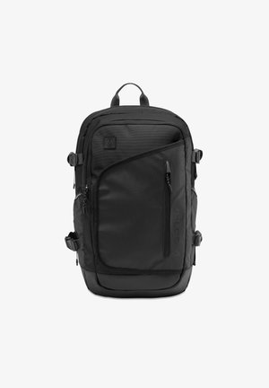 Sac à dos noir avec une surface texturée, plusieurs compartiments zippés, des bretelles réglables et un fond en caoutchouc pour la durabilité.
