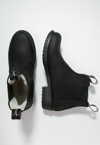 Black ankle boots made of smooth leather, featuring elastic side panels, textured soles, pull tabs, and a soft lining for comfort.