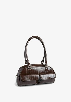 Lille mørkebrun håndtaske i laklæder med to forlommer med klap og dobbelte skulderremme, stående på en hvid overflade.