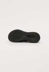 Fekete sneaker talp, amely texturált, bordázott mintázattal rendelkezik a tapadás érdekében. Lekerekített forma, vastag, rugalmas gumi szerkezettel.