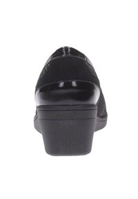 Zapato de tacón alto negro con parte superior texturizada y acentos de charol suave. Presenta una puntera redondeada y un tacón grueso resistente.