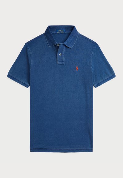 Zils polo krekls no mīksta kokvilnas, ar klasisku apkakli, divu pogu aizdari un mazu sarkanu izšuvētu logotipu uz krūtīm.