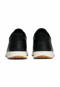 Sneakers neri in pelle con finitura liscia e dettagli in camoscio, dotati di una suola bianca con fondo in gomma color caramello e dettagli con marchio sul tallone.