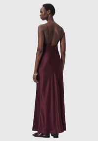 Burgundy satin maxiklänning med ett figursytt liv, tunna band och en öppen rygg. Flödande kjol med en slät textur, utrustad med sid sömsdetaljer.