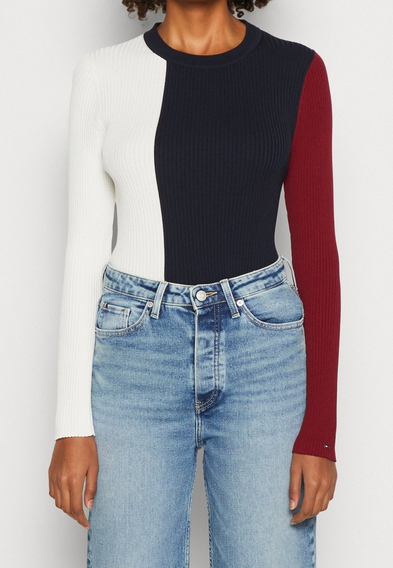 Ribattu pitkähihainen paita, jossa on väriblokkiosat valkoisena, laivastonsinisenä ja viininpunaisena. Yhdistetty vaalean sinisiin farkkuihin.