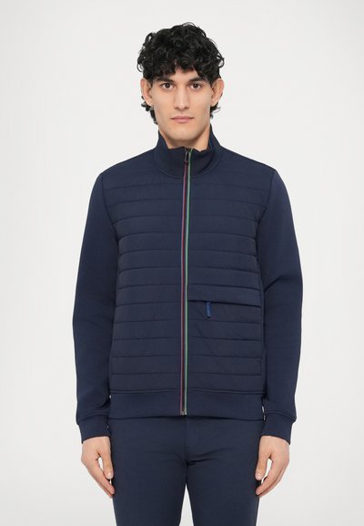 Giacca blu navy con zip, parte frontale trapuntata, collo a coste, cerniera di colore contrastante e dettaglio di tasca laterale. Tessuto in misto cotone.