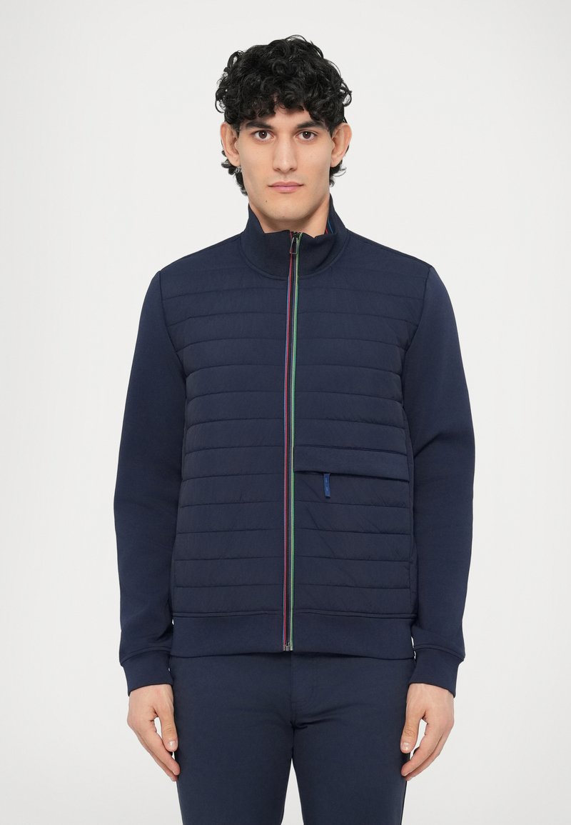 Tumesinine lukuga jakk, millel on tikitud esikülg, soonikkoes krae, kontrastse värvi lukk ja küljetasku detail. Puuvilla segu kangas.