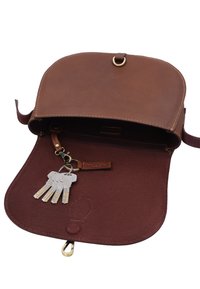 Braune Ledertasche geöffnet, um einen angebrachten Schlüsselanhänger zu zeigen, der fünf silberne Schlüssel im Inneren der Klappe hält.