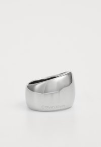 Hõbe metallrõngas sujuva ja kumerda disainiga. Rõnga küljele on muljutud brändi nimi "Calvin Klein". Peegeldav pind rõhutab kuju.