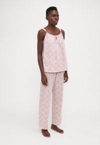 Lättvikts, rosa pyjamasset med en ärmlös topp med ett nyckelhål och löst sittande, mönstrade byxor. Mjuk tyg med blommönster.