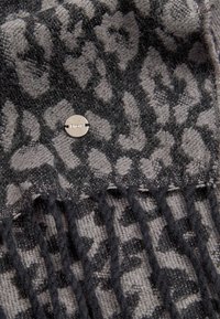Sciarpa lavorata a maglia grigia con un motivo leopardato nero, con frange a un'estremità e un'etichetta metallica con la scritta "Brax." Texture morbida.