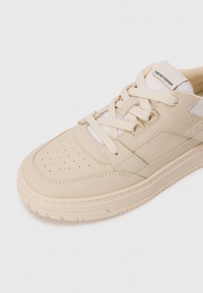 Beige lädersneaker med perforerad tå, texturerad beige sula, krämfärgad snörning och nät-tunga märkt Emporio Armani.