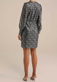 Short, black and white zigzag patterned dress with long sleeves, cinched waist, and a straight hem. Sheer material with a textured finish.