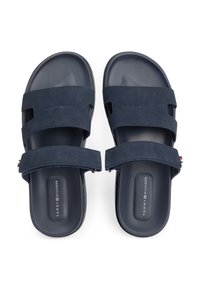 Σαγιονάρες σε ναυτικό μπλε χρώμα με δύο φαρδιές σουέντ λουριά και σόλα από καουτσούκ με υφή, με διακριτική σήμανση στο πέλμα.