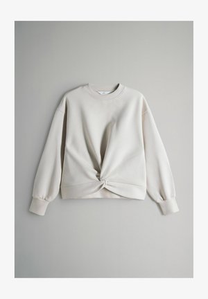 Jasnoszara bluza z okrągłym dekoltem, ozdobą w postaci zebranej z przodu kokardy oraz długimi bufiastymi rękawami. Tkanina wydaje się miękka i teksturowana.