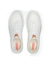 Zapatillas de piel blanca con una textura suave, punta redonda y detalles perforados. Presentan cordones blancos y un logo rojo en la plantilla.