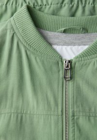 Grüne Bomberjacke mit Reißverschluss, geripptem Kragen und strukturierter Oberfläche. Verfügt über ein graues Innenfutter und kontrastierende Nähte.