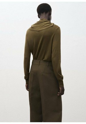 Bluză cu mânecă lungă de culoare verde măsliniu, cu un decolteu drapat, asortată cu pantaloni maro cu talie înaltă, ce au buzunare laterale și o textură netedă.