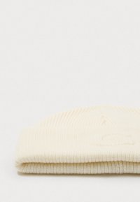 Crème rib gebreide beanie met een omgeslagen rand, met subtiele textuur en minimalistisch design, gemaakt van zacht, flexibel materiaal.