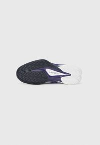 Lilla og hvit atletisk sko såle med bølgeformet dekkmønster for grep, med "LACOSTE" merke på siden.