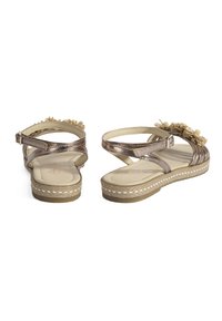 Metallic bronze Sandalen mit verstellbaren Knöchelriemen, strukturiertem Fußbett und dekorativen Pom-Pom-Akzenten. Plateausohle mit weißen Stichdetails.