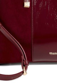 Sac à main bordeaux doté de textures en daim et en cuir brillant, d'un accent en métal doré et d'une longue bandoulière réglable.