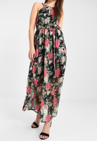 Blommig maxiklänning med svart bakgrund och mönster av rosa och gröna rosor, elastisk midja och halterneck.