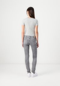 Gray fitted t-shirt with short sleeves paired with gray skinny jeans. White sneakers visible at the feet. Simple and sleek design.
