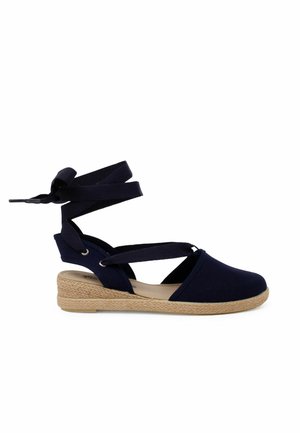 Espadrille bleu marine avec une tige en toile, semelle en jute tressé et bretelles en tissu croisées. Dispose d'un design à bout fermé et d'une forme arrondie.