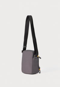Bolso de hombro gris con un patrón texturizado, forma rectangular, correa negra ajustable y detalle de tirador de cremallera amarilla.