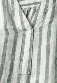 Top in lino con righe verticali verdi e bianche, dotato di scollatura a V, dettaglio di tessuto arricciato e cuciture ordinate lungo i bordi.