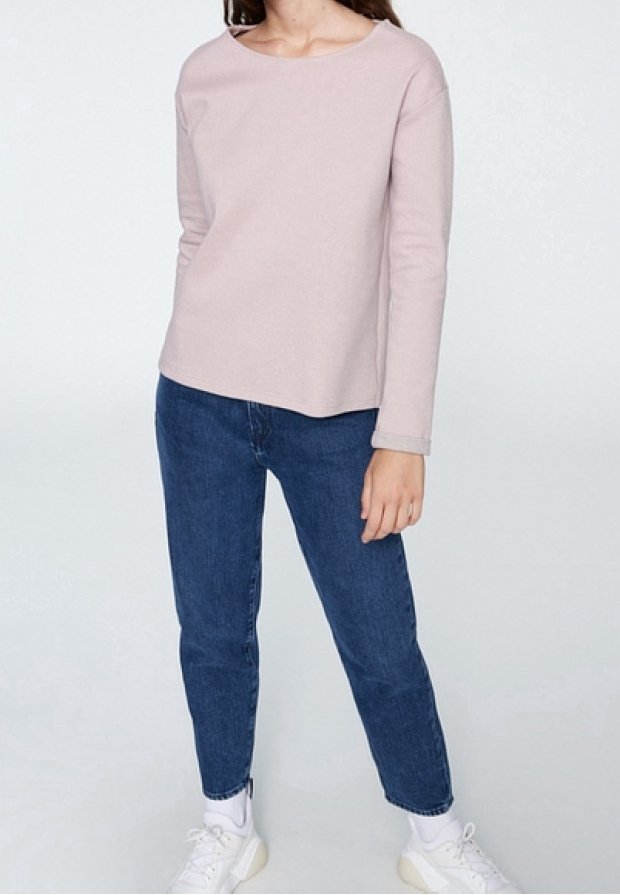 Haut rose clair à manches longues avec un col arrondi, associé à un jean tapered bleu foncé et des baskets blanches. Texture lisse, design décontracté.