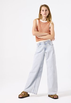 Top sin mangas de ganchillo en naranja y crema, combinado con jeans de tiro ancho en azul claro y sandalias marrones con un acento dorado.